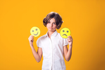 Upset girl holds emoticons with happy and sad emotions. - obrazy, fototapety, plakaty