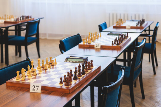 Chess tournament, kids and adults participate in chess match game outdoors in indoor hall, players of all ages play, competition in chess school club with chessboards on a table