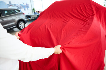 Man removes a red cover from a car