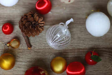 Pine cones and red, golden and white Christmas ornaments on wooden background. Selective focus.