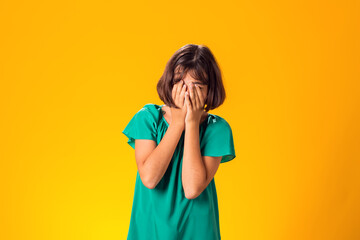 Sad kid girl over yellow background. Frustration concept
