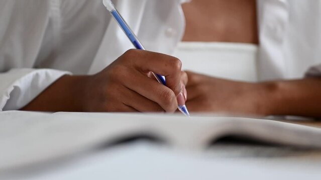 Student preparing for college test, exam, writing notes, making summary for class report. Learning workplace table, hands with pen close up