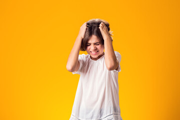 Sad kid girl holding her head over yellow background. Frustration concept