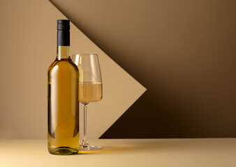 Bottle and glass of white wine on a beige background. - obrazy, fototapety, plakaty