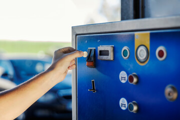 Close up of hand putting coin into a coin machine at car wash.