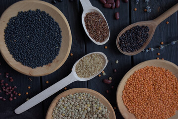 Lentils beans and rice. Organic gluten free dry cereals and legume on black wood background. Black...
