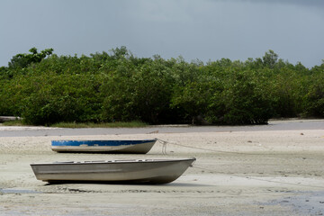 Fototapeta premium Two fishing boats are docked on the sand of a beach at the exit to the sea. City of Santo Amaro, Bahia.