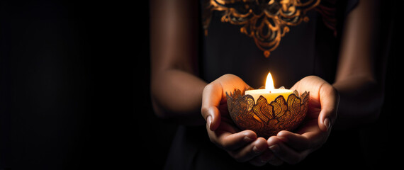 Woman hand holding candle on a dark background