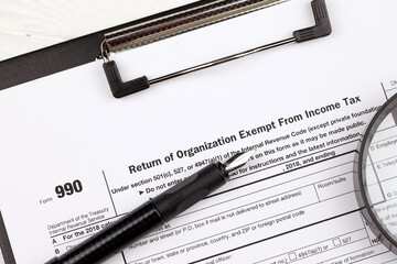 Form 990 Return of organization exempt from income tax on A4 tablet lies on office table with pen...
