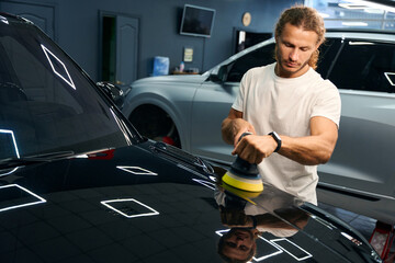 Professional polishes the body of a black car