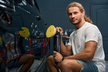 Young man works in a car repair shop