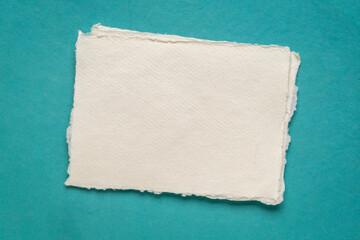 small sheet of blank white Khadi rag paper from India against blue art paper