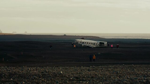 Plainwreck from a distance, walking people nearby, sea at the background, Iceland, Solheimasandur