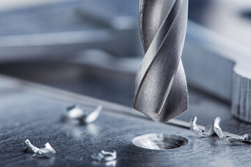 metal drill bit make holes in steel billet on industrial drilling machine