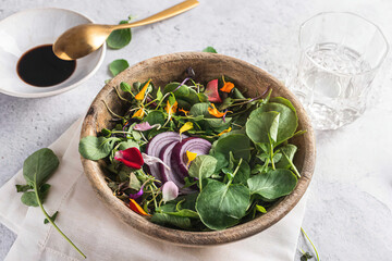 Top view of wooden bowl with tasty salad with sprouts and vegetables placed on table for healthy lunch