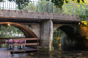 Restaurant table on a river under a bridge, Ljuta, Croatia.