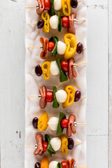 A long narrow platter of antipasto skewers, ready for sharing.