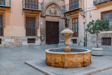 An ancient fountain on a narrow street on a sunny day. Valencia,Spain