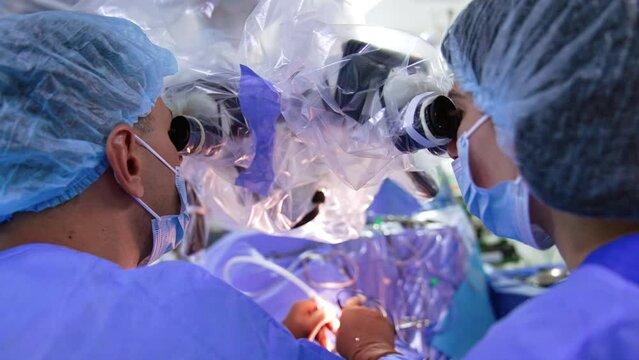Male and female doctors in caps and masks looking at microscope. Rear view close up.