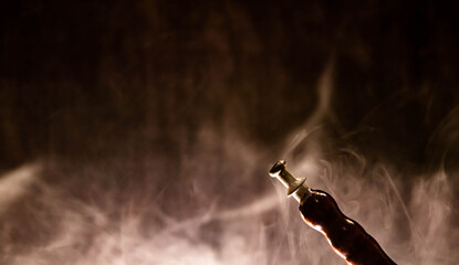 Modern hookah, shisha on a smoky black background with neon lighting and smoke. Place for your text.