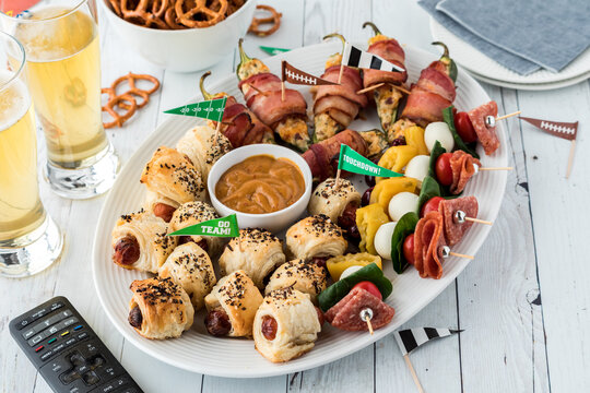 A platter of game day appetizers include pigs in a blanket and jalapeno poppers.