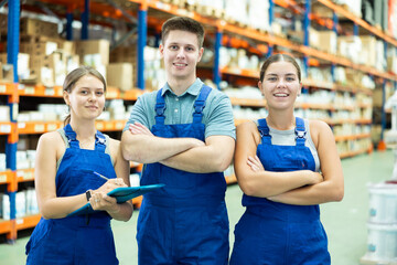 Positive young female and male employees of warehouse of goods for repair and construction are...