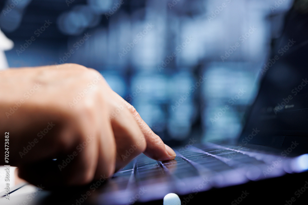 Poster cloud computing company executive using laptop to examine server racks for power fluctuations, close