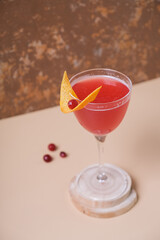 Pink alcoholic cocktail in steamed glasse on wooden podium or pedestal