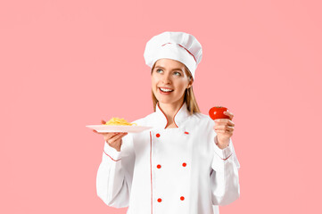 Female chef with tasty pasta and tomato on pink background