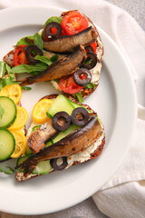 Plate of tasty sandwiches with canned smoked sprats on table
