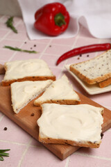 Wooden board of tasty toasts with cream cheese on table