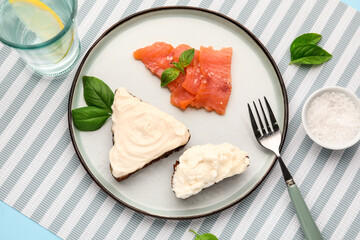 Plate of tasty sandwiches with cream cheese and fish on blue background