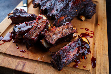 Traditional barbecue burnt chuck beef ribs marinated with spicy rub and served as close-up on a rustic wooden board