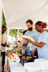 Young black woman and caucasian man cook and donate free meal at a food drive to the poor and...