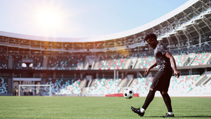 African American man playing football on the stadium field. A man runs with a soccer ball across the field.