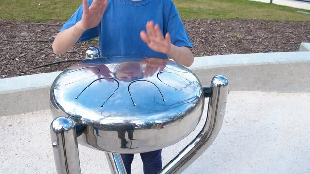 Musical child play drum in outdoor park. A little girl with interest play drum pn playground during day time.