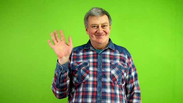 Friendly senior man waves palm for greeting or goodbye sign.