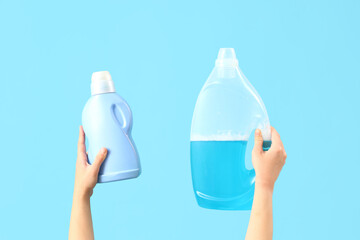 Woman with bottles of laundry detergent on blue background