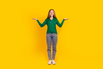 Fototapeta na wymiar Full size portrait of positive nice girl hands hold demonstrate empty space proposition isolated on yellow color background