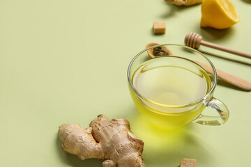 Glass cup of ginger tea with lemon on green background