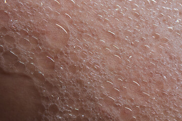 Fototapeta premium Soap foam on human skin, detailed vertical photo, foam texture on skin
