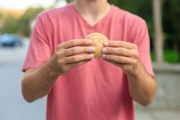 Guy's hand holds mini bread, snack and fast food concept. Selective focus on hands with blurred background