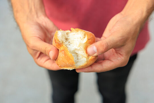 A man's hand holds a round bun, snack and fast food concept. Selective focus on hands with blurred background
