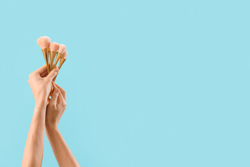 Woman with makeup brushes on blue background