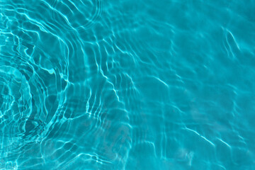 Transparent turquoise clear water surface texture with ripples, waves and rings in sunlight....