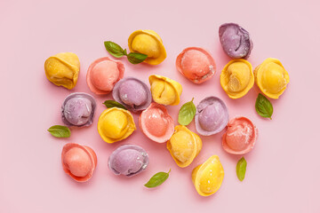 Colorful raw dumplings with basil on pink background