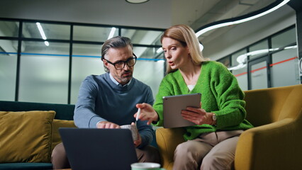 Obraz premium Focused coworkers discussing business at sofa. Involved teammates brainstorming