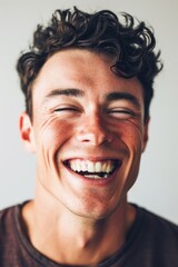 Obraz premium A young man with curly hair smiling directly at the camera. Suitable for various uses