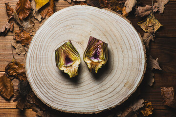 Raw organically grown artichoke flower buds on wooden table