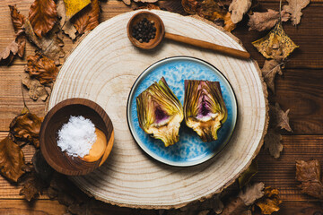 Raw organically grown artichoke flower buds on wooden table